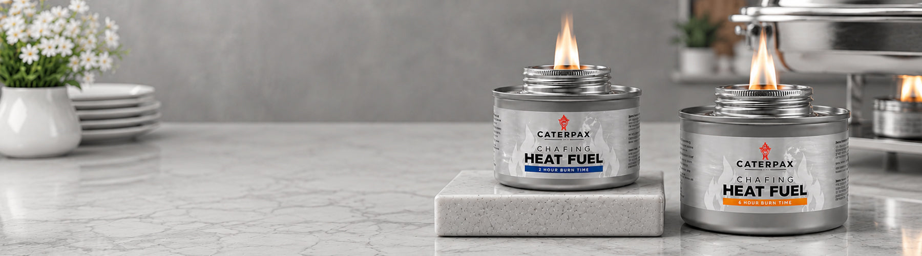 Two cans of Caterpax heat fuel on a kitchen counter with flames.